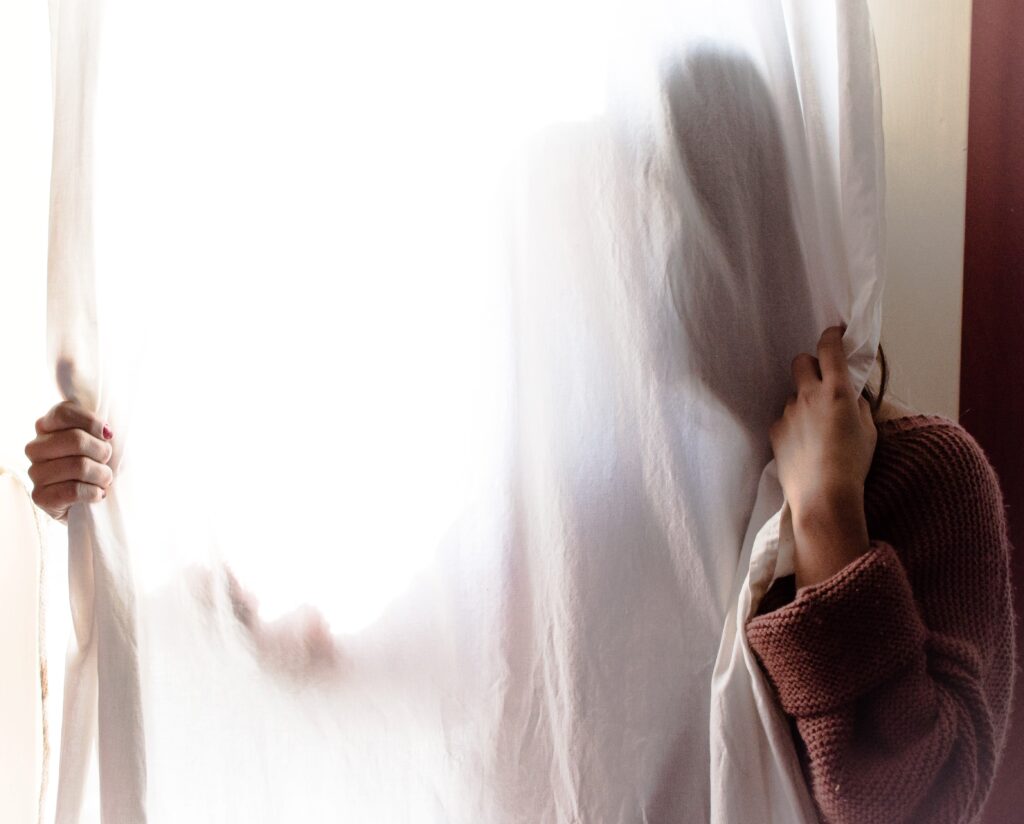 Adulte caché derrière un rideau voile blanc pour présenter la Règle N°4 : Je me protège des gens négatifs